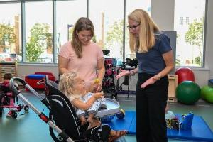 Two women speaking with a pediatric patient in a wheelchair