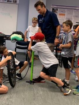 Summer camp participants pumping a bicycle tire